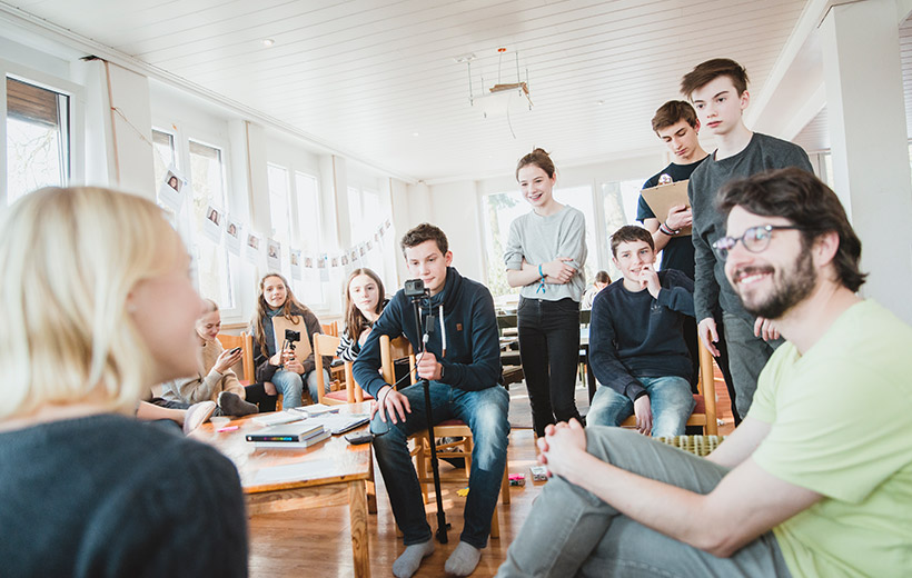 Das Bild zeigt Pfr. Offenberger während er von seinen Konfis interviewt wird.